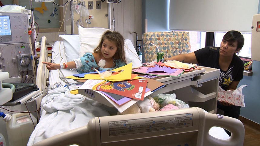 A young girl sits up in a hospital bed