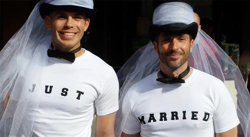 Two men stand proudly in shirts that read JUST and MARRIED