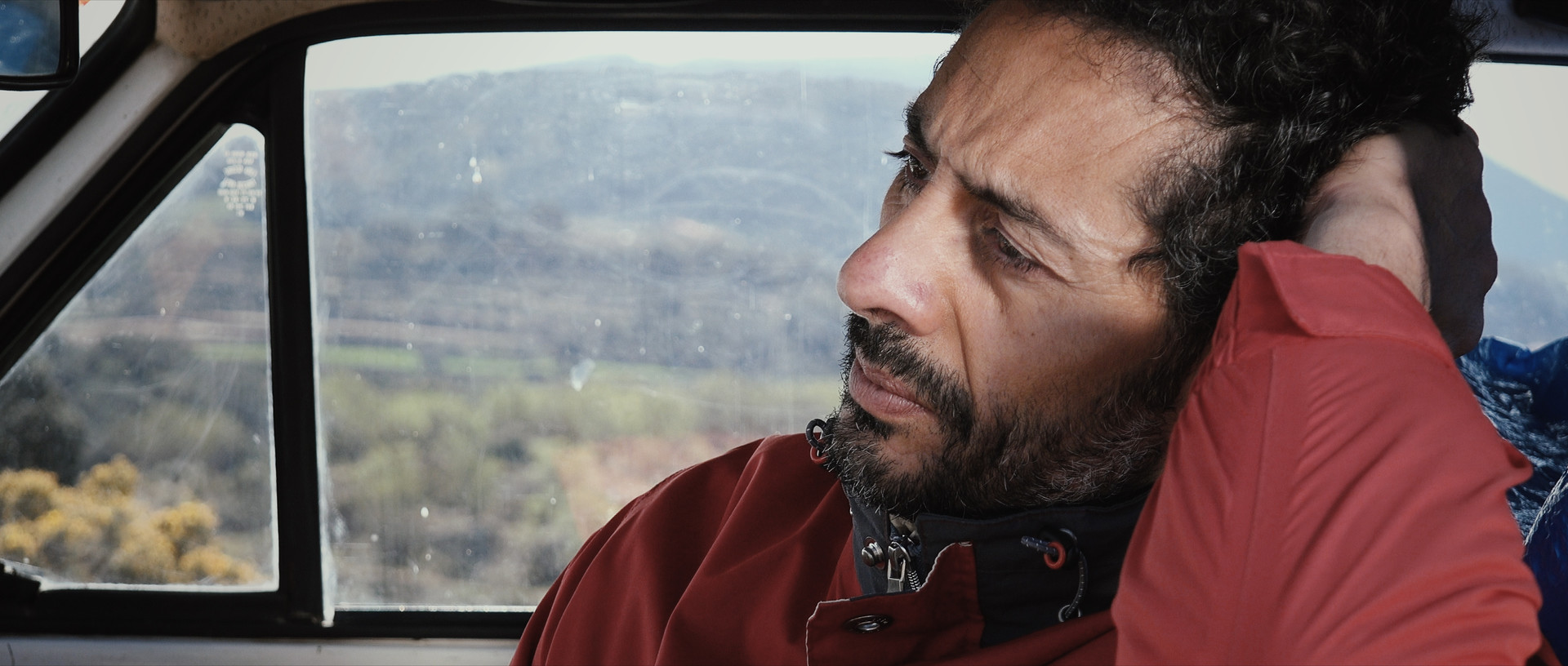 A man looks lost in thought inside the cab of an automobile.