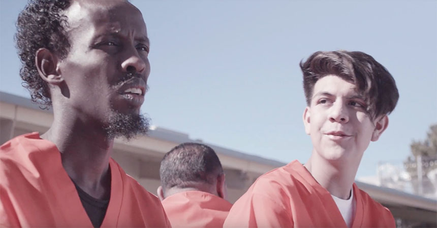 Two men in orange uniforms converse.