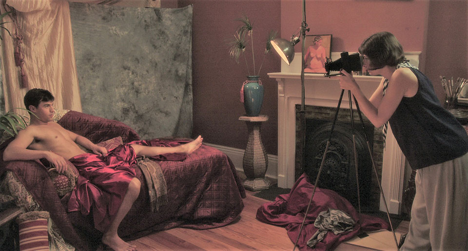 A woman photographs a semi-nude man.