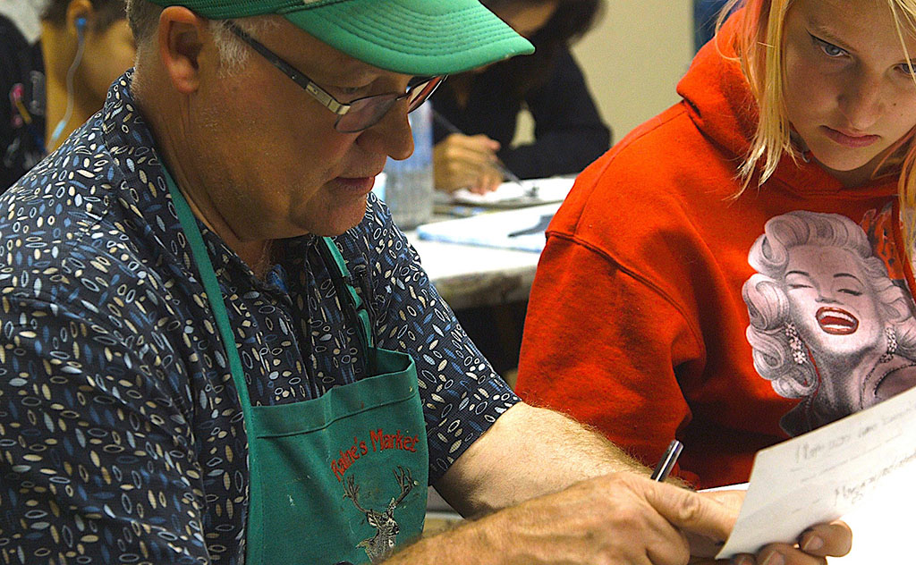 An art teacher assists a student with a project.